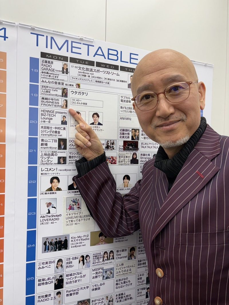 番組タイムテーブルの前に立つ久野康成